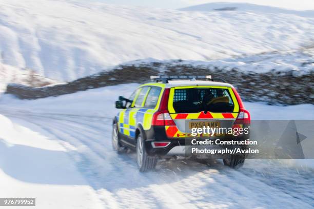 Police car tries to get over the Kirkstone Pass road above Windermere after it is blocked by spindrift and wind blown snow, Lake District, UK.