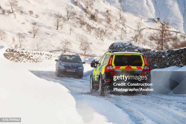 Police car tries to get over the Kirkstone Pass road above Windermere after it is blocked by spindrift and wind blown snow, Lake District, UK.