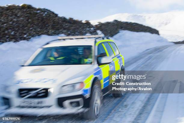 Police car tries to get over the Kirkstone Pass road above Windermere after it is blocked by spindrift and wind blown snow, Lake District, UK.