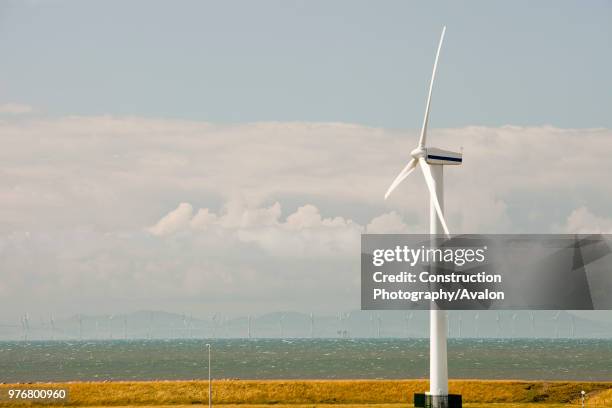 An onshore wind turbine on the outskirts of Workington, Cumbria, UK In the background is the new Robin Rigg offshore wind farm in the Solway Firth...