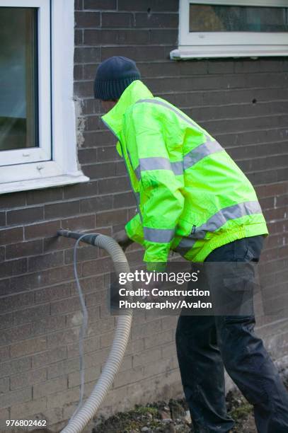 Installing cavity wall insulation into a house to increase its energy efficiency and reduce the carbon emmissions from central heating, Ambleside,...