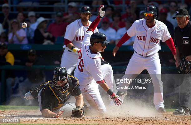 Catcher Erik Kratz of the Pittsburgh Pirates cannot handle the throw as infielder Jose Iglesias of the Boston Red Sox scores during a Grapefruit...