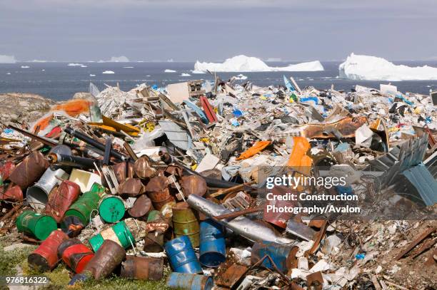 Rubbish dumped on the tundra outside Illulissat in Greenland with icebergs behind from the Sermeq Kujullaq or Illulissat Ice fjord The Illulissat ice...