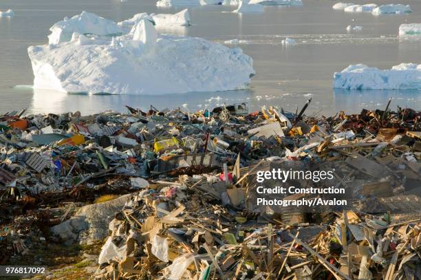 Rubbish dumped on the tundra outside Illulissat in Greenland with icebergs behind from the Sermeq Kujullaq or Illulissat Ice fjord The Illulissat ice...