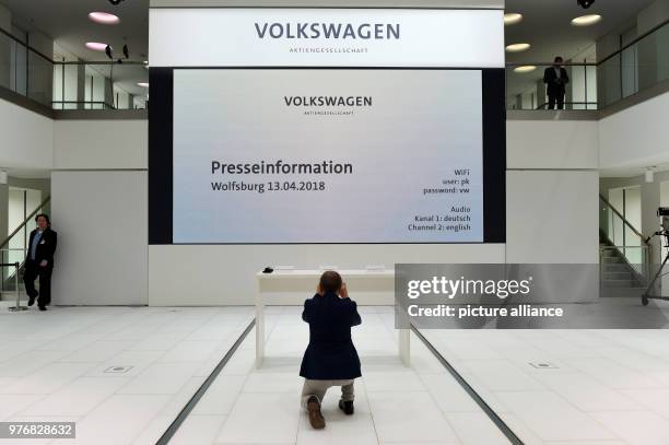 April 2018, Germany, Wolfsburg: A journalist photographing the table with the name plates just before the start of a press conference after...