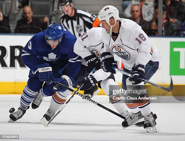 Luca Caputi of the Toronto Maple Leafs battles with Mike Comrie and Ethan Moreau of the Edmonton Oilers in a game on March 13, 2010 at the Air Canada...