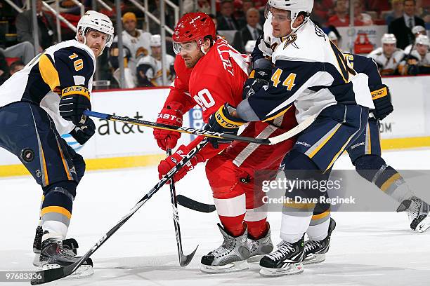 Henrik Zetterberg of the Detroit Red Wings skates between the defense of Henrik Tallinder of the Buffalo Sabres and teammate Andrej Sekera during an...