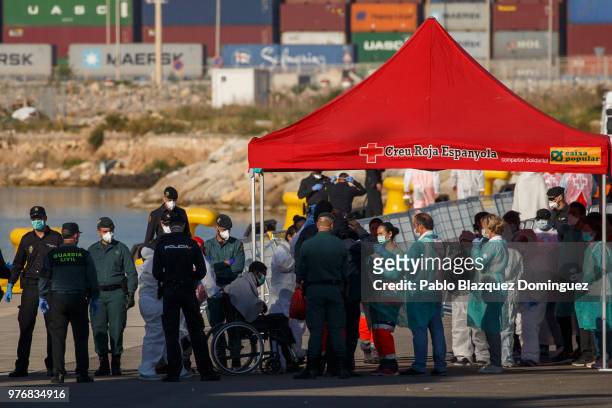 Health workers help a migrants on a wheelchair as he disembarks from the Italian coast guard vessel Dattilo at the Port of Valencia on June 17, 2018...