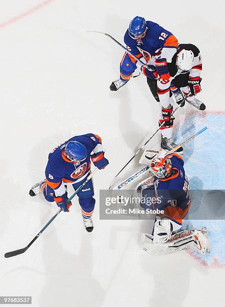 Goaltender Dwayne Roloson, Josh Bailey and Bruno Gervais of the New York Islanders defend against Travis Zajac of the New Jersey Devils on March 13,...