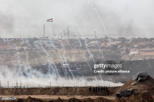 Picture taken from the Israeli side shows tear gas canisters being fired at Palestinian protesters during clashes with Israel security forces along...