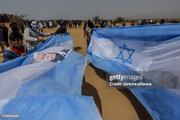 Palestinian protesters carry an Israeli flag bearing the picture of US President Donald Trump before burning it during clashes with Israeli security...