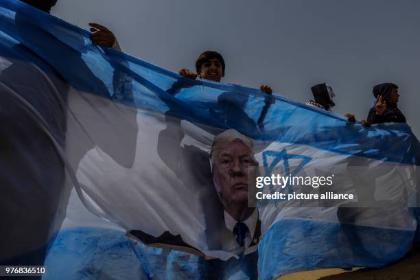 Dpatop - Palestinian protesters carry an Israeli flag bearing the picture of US President Donald Trump before burning it during clashes with Israeli...