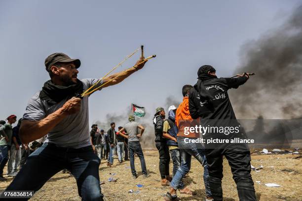 Palestinian protester uses a slingshot to hurl stones during clashes with Israeli security forces along the borders between Israel and Gaza Strip,...