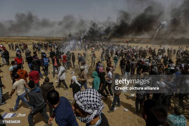 Dpatop - Palestinian protesters run for cover from Israeli tear gas fired during clashes along the borders between Israel and Gaza, east of Khan...