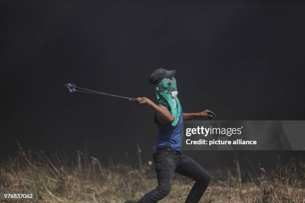 Palestinian protester uses a sling to hurl stones at Israeli security forces during clashes along the Israel-Gaza border, east of Gaza City, Gaza...