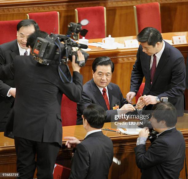 Chinese President Hu Jintao takes off his glasses after signing a document at the closing session of the National People's Congress at the Great Hall...