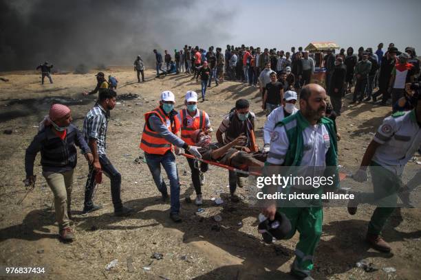 Dpatop - Palestinians carry fellow protester on a stretcher after being injured during clashes with Israeli security forces along the Israel-Gaza...