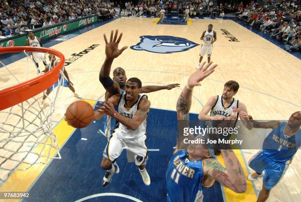 Mike Conley of the Memphis Grizzlies shoots between Johan Petro and Chris Andersen of the Denver Nuggets on March 13, 2010 at FedExForum in Memphis,...