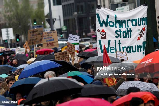 April 2018, Germany, Berlin: Portestors demonstrate against housing shortage and rent increases and carry a sign reading 'Wohnraum statt Weltraum! ....
