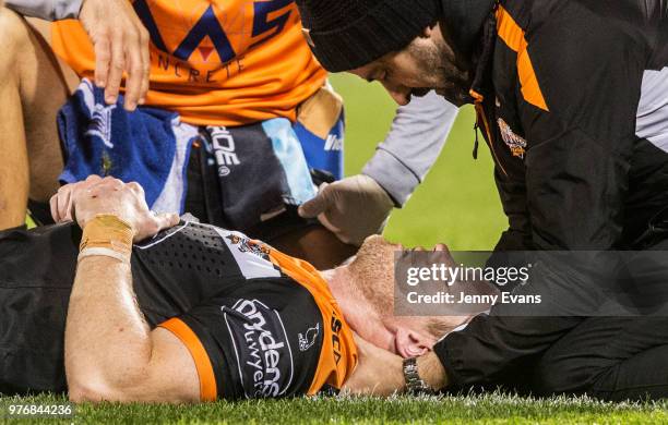 Chris Lawrence of the Tigers is assisted by Tigers staff after an injury during the round 15 NRL match between the Wests Tigers and the Canberra...