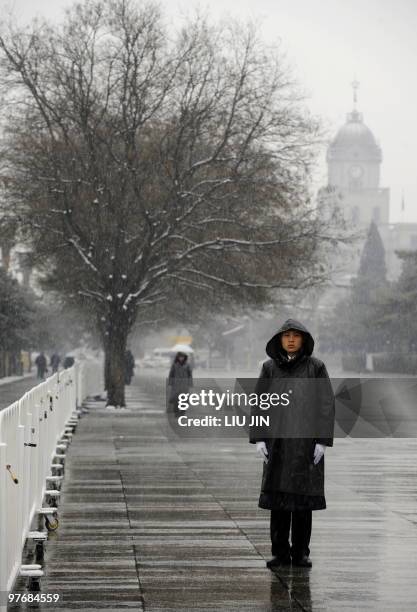 Paramilitary police stand guard in the snow during the closing session of the National People's Congress at the Great Hall of the People in Beijing...