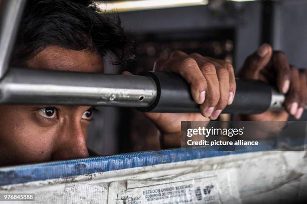 April 2018, Mexico, Mexico-City: A man holds on to a bar of a vehicle which is meant to bring him and and a group of migrants from Central America to...