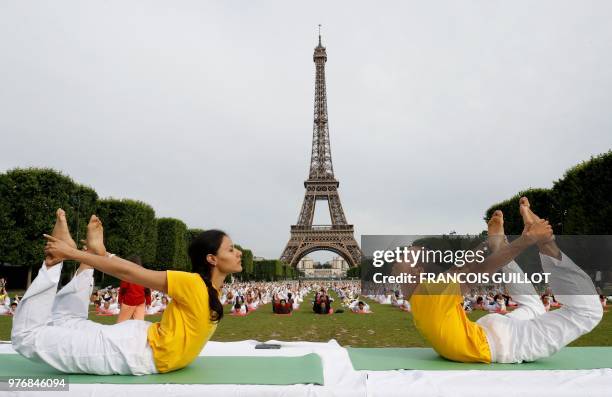 Participants take part in a mass yoga event on the Champs de Mars in front of the Eiffel tower in Paris on June 17, 2018 in celebration of the...