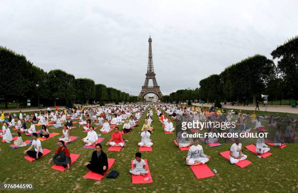 Participants take part in a mass yoga event on the Champs de Mars in front of the Eiffel tower in Paris on June 17, 2018 in celebration of the...