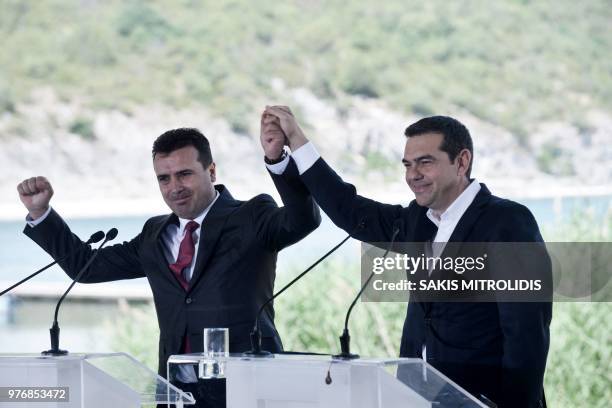 Greek Prime Minister Alexis Tsipras and Macedonian Prime Minister Zoran Zaev raise their hands during a signing ceremony between officials from...