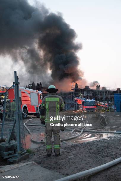 Firefighters monitors a dense smoke rises from a fire has broke out on the hall of the former slaughterhouse at the Landsberger Allee, in Berlin,...