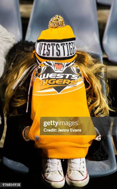 Young girl covers her face as her team are behind during the round 15 NRL match between the Wests Tigers and the Canberra Raiders at Campbelltown...