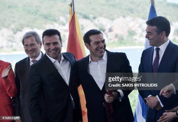 Greek Prime Minister Alexis Tsipras holds the tie of Macedonian Prime Minister Zoran Zaev as EU enlargement commissioner Johannes Hahn and Macedonian...