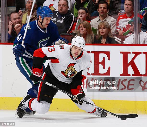 Andrew Alberts of the Vancouver Canucks checks Jarkko Ruutu of the Ottawa Senators during their game at General Motors Place on March 13, 2010 in...