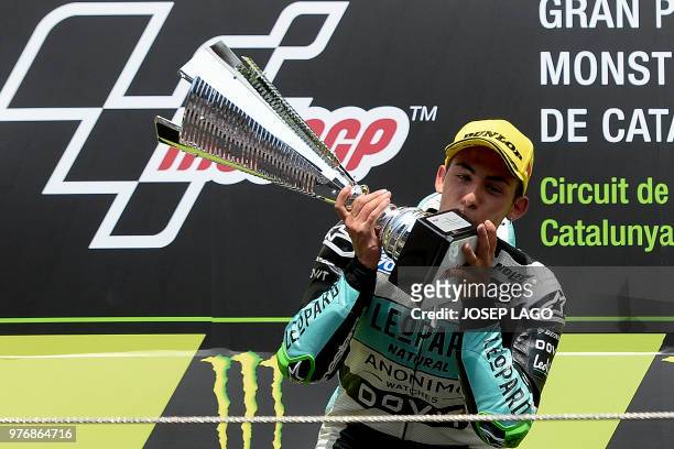 Honda Leopard Racing Italian's rider Ena Bastianini kisses the trophy as he celebrates on the podium after winning the Catalunya Moto3 Grand Prix...