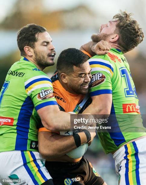 Esan Marsters of the Tigers is tackled by Aiden Sezer and Elliott Whitehead of the Raiders during the round 15 NRL match between the Wests Tigers and...