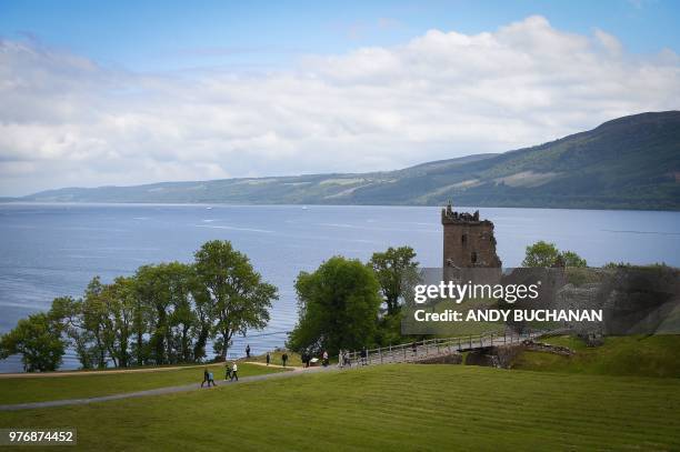 Tourists take in Urquhart Castle on the banks of Loch Ness in the Scottish Highlands, Scotland on June 10, 2018.