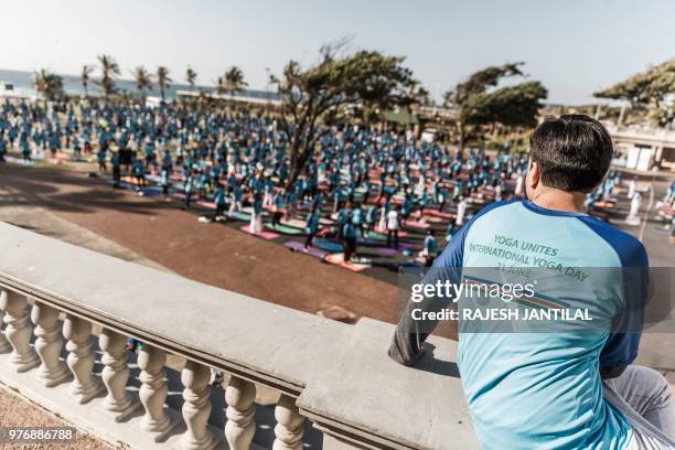 Man watches people attending a yoga session at North Beach on June 17, 2018 in Durban, South Africa, ahead of the International Day of Yoga on June...