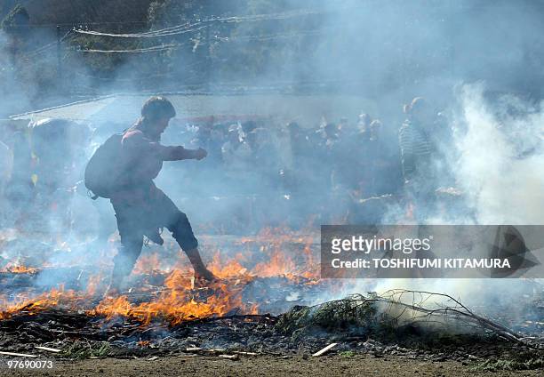 Buddhist devotee walks barefoot through the flames during the "Hi-watari", or fire walking ceremony, to herald the coming of spring at the Yakuoin...