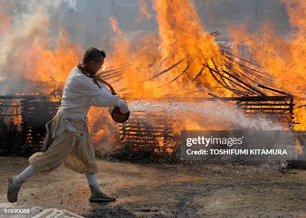 Buddhist ascentic monk throws water to control the flames prior to the "Hi-watari", or fire walking ceremony, to herald the coming of spring at the...