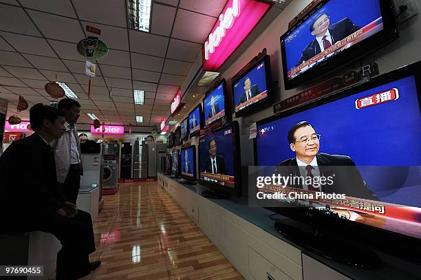 Customers watch the live broadcast of Chinese Premier Wen Jiabao's press conference after the closing of the National People's Congress in a shop on...