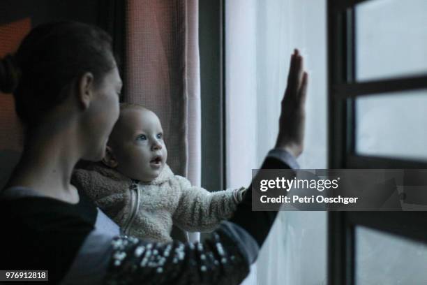 a baby boy learns about the rain. - mother son shower stockfoto's en -beelden