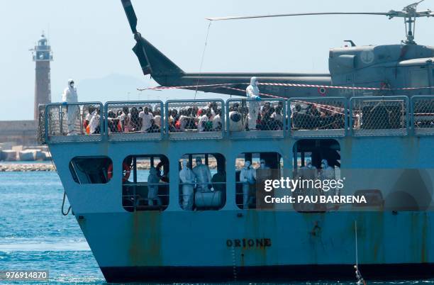 Migrants sit on the deck of the Italian navy ship Orione as the ship enters the port of Valencia on June 17, 2018. - The Aquarius rescue ship with...