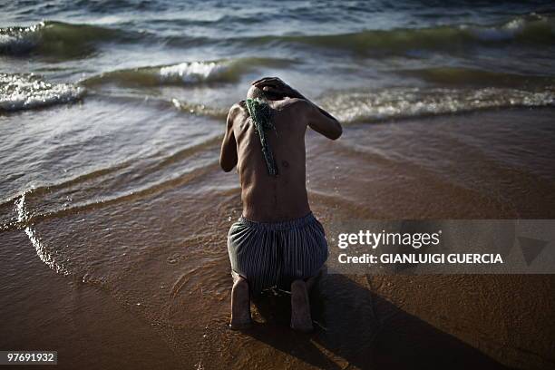 An elderly Angolan man washes himself in the water of Atlantic ocean on January 27, 2010 on the beach of Benguela, Angola. The die is cast for the...