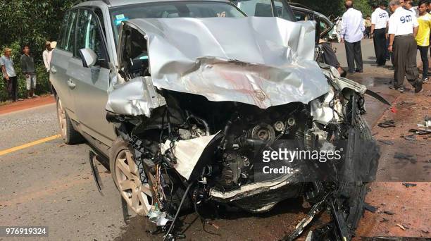 Graphic content / People look at the damaged car carrying Cambodian Prince Norodom Ranariddh and his wife Ouk Phalla, shown in the foreground,...