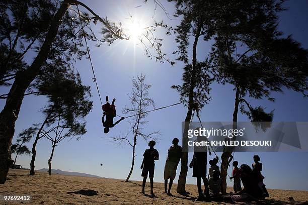 Angolan children watch a boy swinging on a rope on a beach in Benguela on January 18, 2010 during the African Nations Cup CAN2010 football tournament...