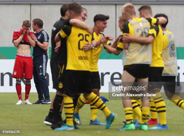 Team coach Holger Seitz of FC Bayern Muenchen comforts his player as players of Borussia Dortmund celebrate after winning the B Juniors German...