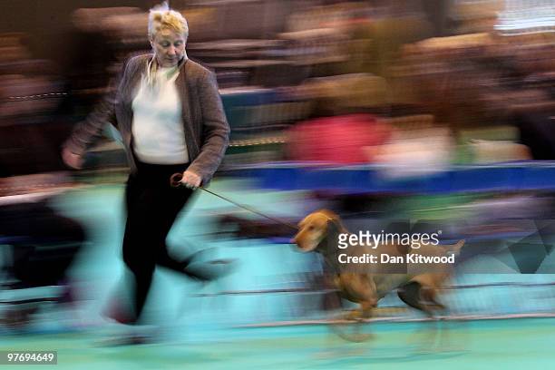Woman runs with her dog in the judging arena during the fourth and final of the annual Crufts dog show at the National Exhibition Centre on March 14,...