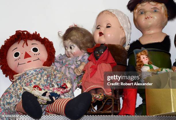 Shelf filled with dolls, including a Raggedy Ann doll, for sale in a Santa Fe, New Mexico, antique shop.