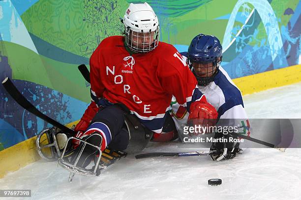 Helge Bjornstad of Norway controls the puck against Gianluigi Rosa of Italy during the Ice Sledge Hockey Preliminary Round Group B Game between...