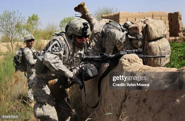 Army Chaplain Carl Subler tries to help a fellow soldier over a wall on March 14, 2010 at Howz-e-Madad in Kandahar province, Afghanistan. He...